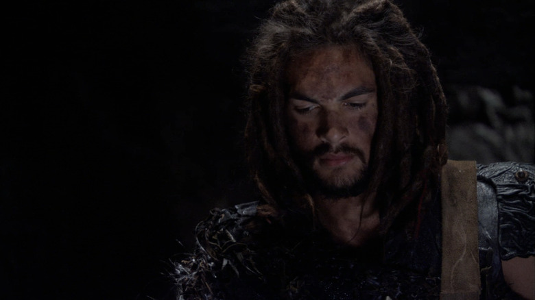 Jason Momoa's Ronon Dex looks down at the floor in a dark cave in Stargate Atlantis