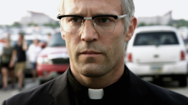 Jason Statham's Parker walks through a parking lot dressed as a pastor in Parker
