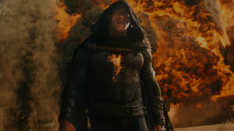 dwayne johnson in his black adam suit surrounded by fire in the movie black adam