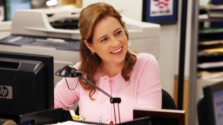 Pam sitting at her desk smiling on The Office