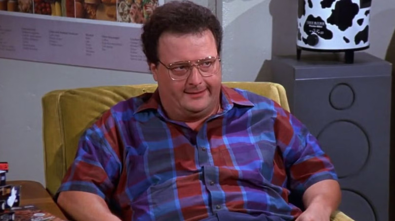 Newman, sitting in a chair looking for a threat against someone a breast scene