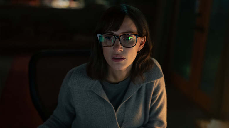 Jessica Chastain as Jodi Goodwin wearing glasses and looking at a reflective computer screen in The Savant
