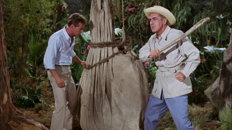 The Professor and Mr. Howell hitting something in a bag, dangling from a tree, on Gilligan's Island