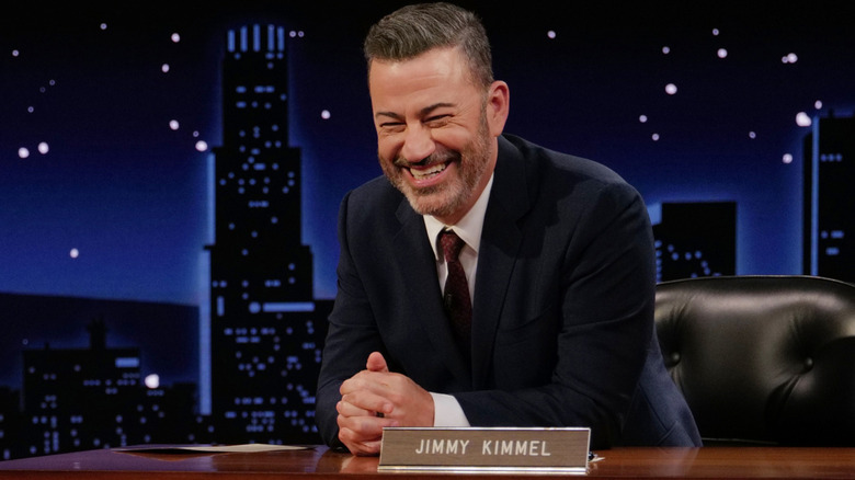 Jimmy Kimmel laughing at his desk on the set of Jimmy Kimmel Live!