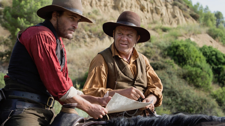 Charlie and Eli Sisters looking at a map on horseback in The Sisters Brothers