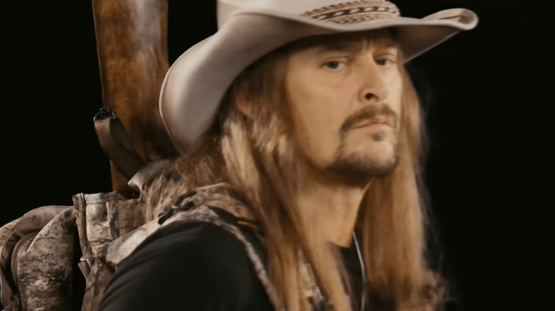 Kid Rock in his music video "Never Quit" wearing a hat with a gun on his back