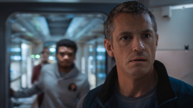 Joel Kinnaman's Edward Baldwin looks concerned as he stands in a hallway in For All Mankind
