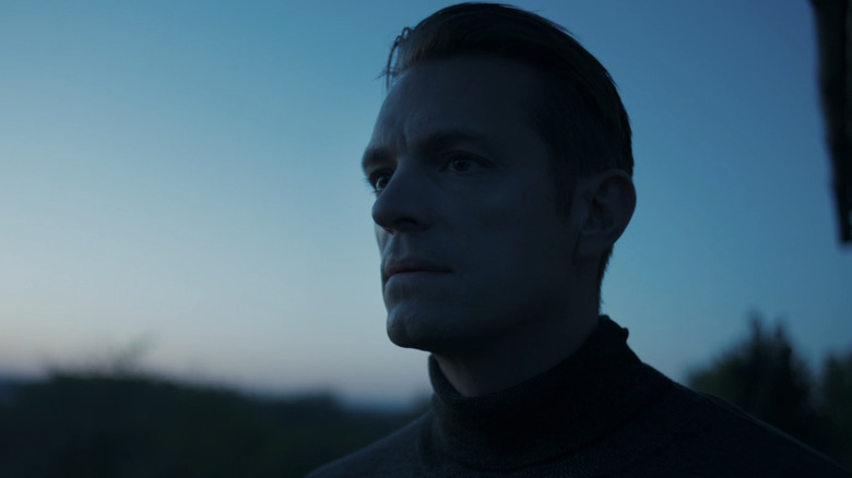 Joel Kinnaman's Erik Heller stands outside looking off into the distance in Hanna