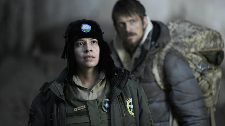 Cara Jade Myers as Ani standing in front of Joel Kinnaman as Harlan in Icefall