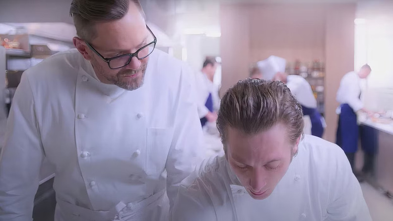 David Fields (Joel Macheel) tends and looks down in the judgment of the Carmey (Jeremy Allen White) in a crowded kitchen with a bear in the bear, both of whom wears white chef coats