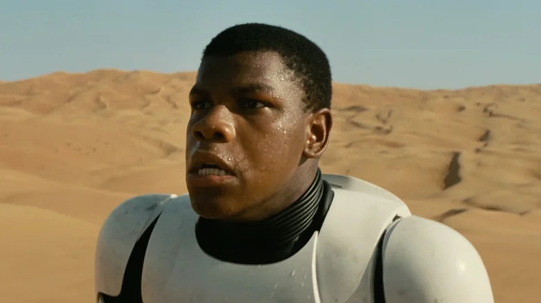 John Boyega as Finn wearing a Stormtrooper armor in the desert in Star Wars: The Force Awakens
