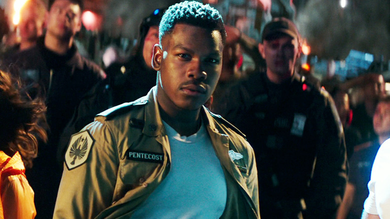 John Boyega's Jake Pentecost stands outside in a crowd looking determined in Pacific Rim Uprising