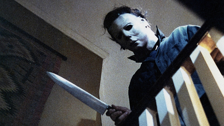 Michael Myers looking over the stair railing with a knife in his hand in Halloween (1978)