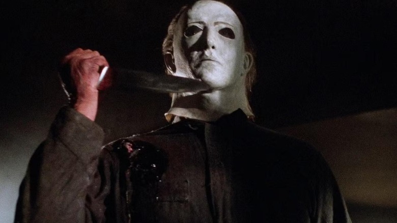 Michael Myers holding a knife up with a stab wound in his shoulder in Halloween 5: The Revenge of Michael Myers