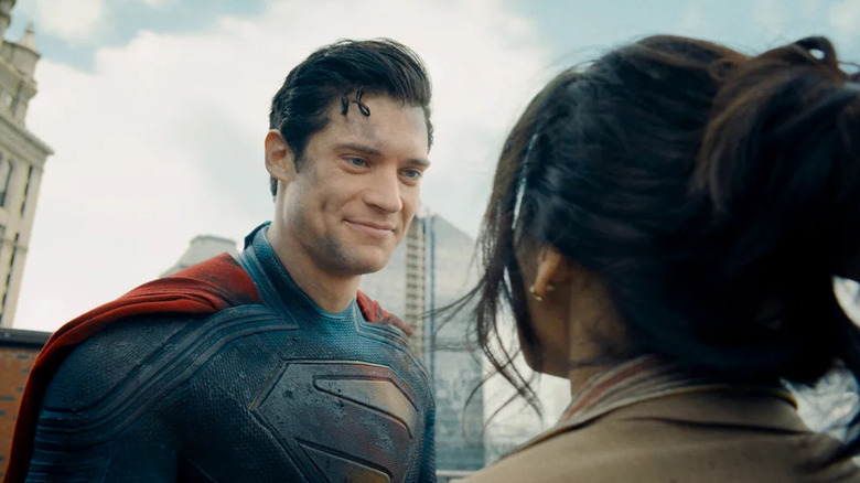 David Corenswet as Superman in Superman, dirty but smiling at a woman he just saved
