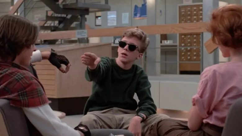 Judd Nelson as Bender, Anthony Michael Hall as Brian wearing sunglasses, and Molly Ringwald as Claire in the library in The Breakfast Club