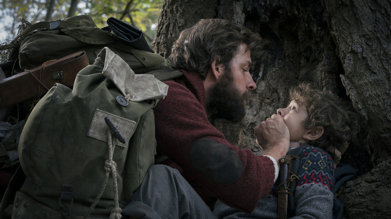 John Krasinski as Lee holding his hand over the mouth of Noah Jupe as Marcus in A Quiet Place