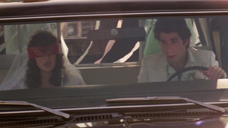 John Travolta' Buford Uan Bud Davis sits alongside Debra Winger's Sissy as they ride in a car in Urban Cowboy.jpg