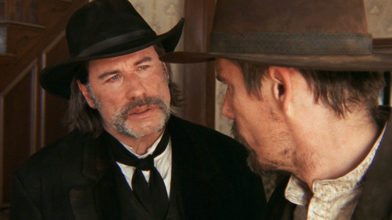 John Travolta's Clyde Martin looks at Ethan Hawke's Paul as they stand in a house in In a Valley of Violence