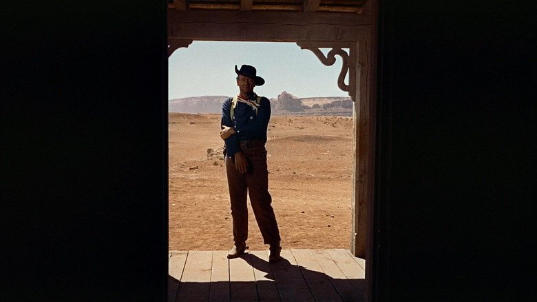 Ethan Edwards (John Wayne) stands in a doorway in The Searchers