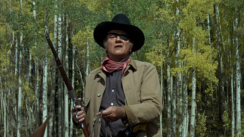 John Wayne's Rooster Cogburn holds a gun as he sits on his horse in True Grit (1969)