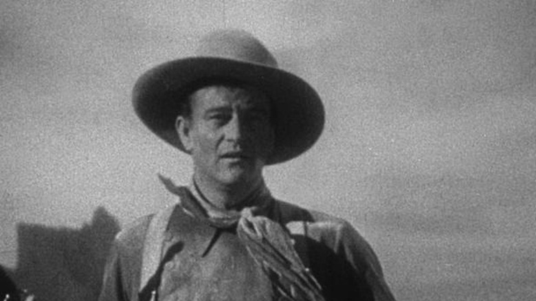 Ringo Kid (John Wayne), dressed in cowboy attire, looks surprised in Stagecoach