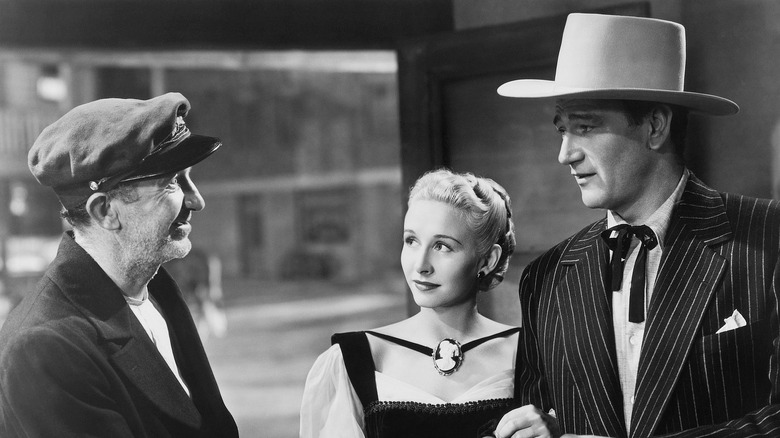 John Wayne as John Devlin standing alongside Vera Hruba Ralston as Sandy Poli, talking to Walter Brennan as Capt. Bounce in Dakota.