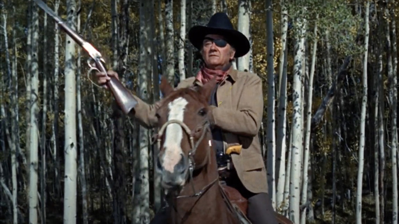 Rooster Cogburn (John Wayne) prepares his rifle in True Grit