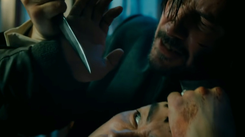 John Wick holding a knife to someone's eye