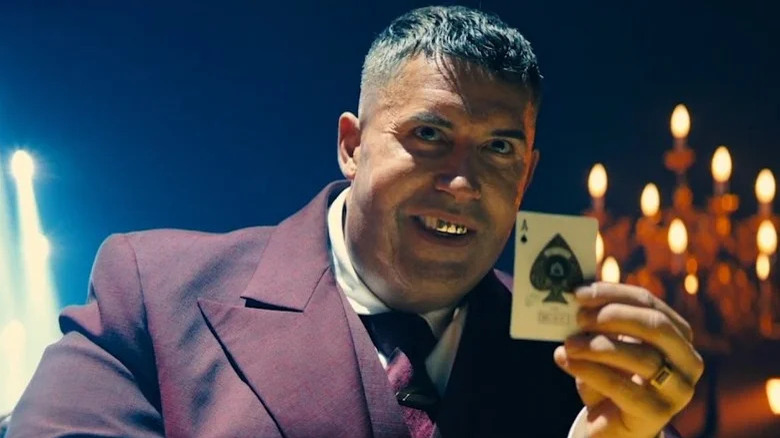 Killing holding playing card in purple suit