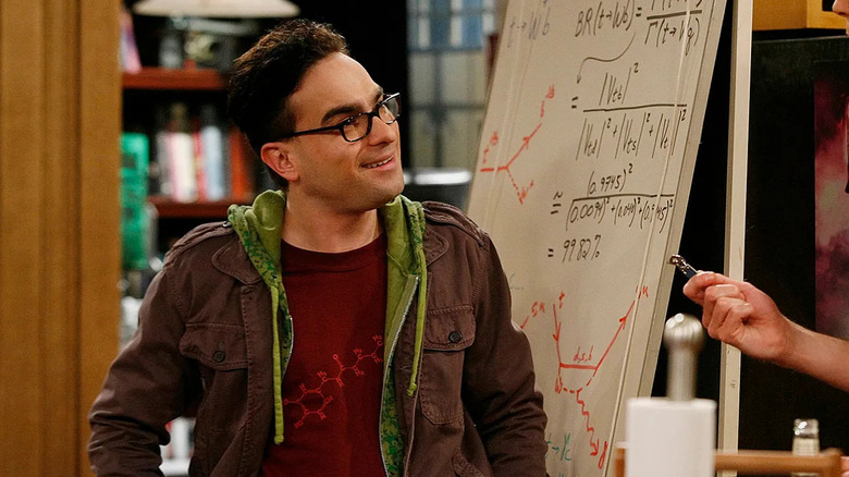Leonard in front of a white board smiling at the theory of the big explosion