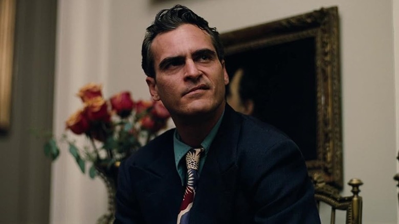 Joaquin Phoenix as Freddie Quill in a chair in his blue suit in The Master