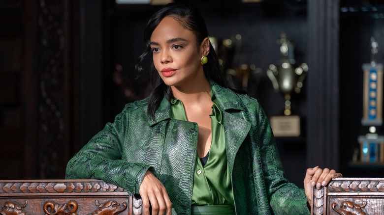 Anna with her hands on two chairs in a green jacket in His & Hers
