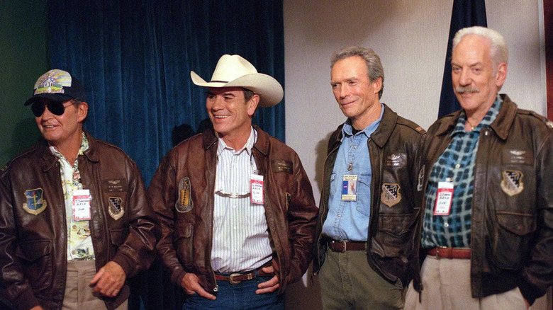 El elenco principal de los vaqueros espaciales de pie juntos en chaquetas de vuelo
