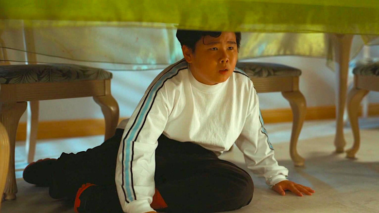 Jacob Kim hids under a table in NOPE