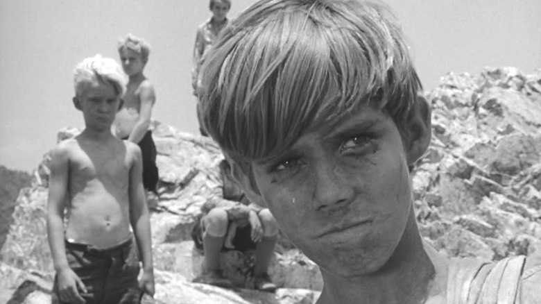 Several boys on a large rock in Lord of the Flies