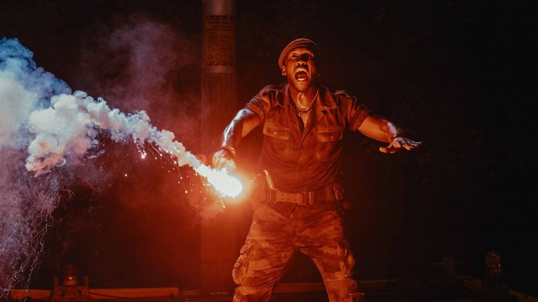 Mahershala Ali as Kincaid lighting up a flare in front of the mutant dinosaur in Jurassic World Rebirth