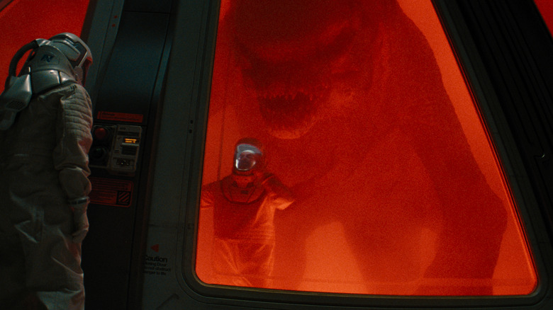 D-REX Silhoutged with red lights sneaks behind a world at the door of an explosion in a new new birth