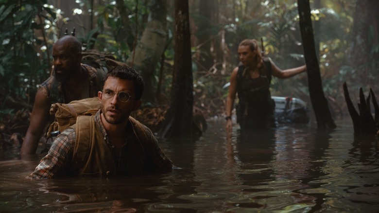 Kincaid, Loomis, and Zora walk through a swamp in Jurassic World Rebirth