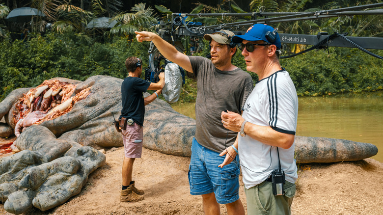 Director Gareth Edwards directing a crew member in front of a giant dinosaur carcass on the set of Jurassic World Rebirth