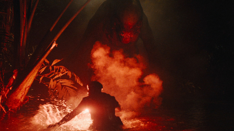 Mahershala Ali's Kincaid lighting up a flare in front of a mutant dinosaur in Jurassic World Rebirth