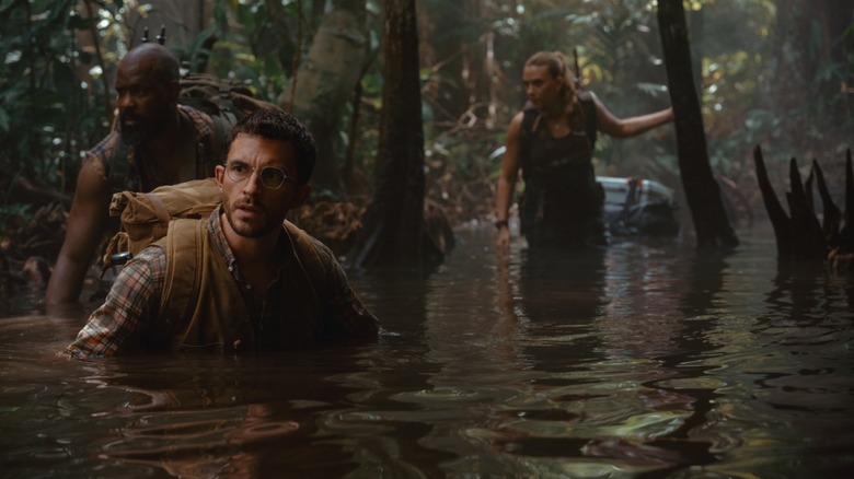 Kincaid, Loomis, and Zora walk through a swamp in Jurassic World Rebirth