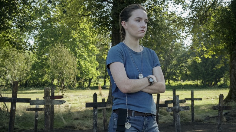 Abby with her arms crossed outside by a graveyard on The Last of Us