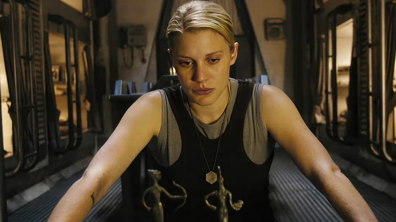 Katee Sackhoff as Starbuck in Battlestar Galactica, pensively looking at figurines