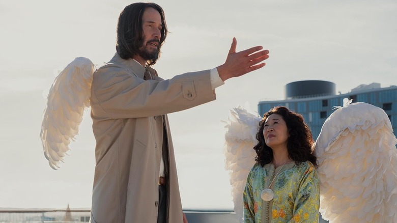 Keanu Reeves as Gabriel and Sandra Oh as Martha standing on a rooftop in Good Fortune