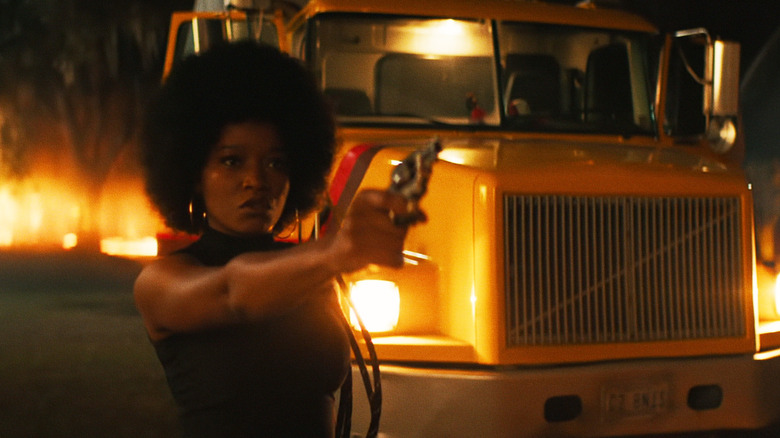Kik Palmer in the role of Alice aims at a pistol in Alice