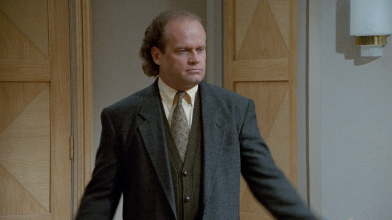 Frasier Crane está parado en su apartamento con un traje Frasier.