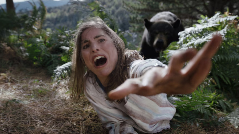 A young woman crawls away in terror from the Cocaine Bear