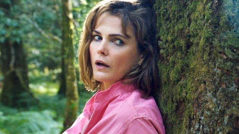 Keri Russell as Sari is hiding behind a tree from the Cocaine Bear
