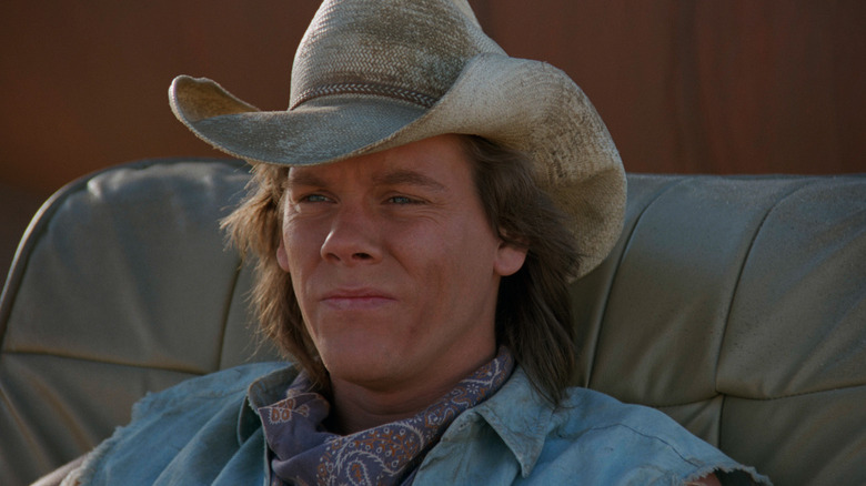 Kevin Bacon as Val McKee sitting outside in his cowboy hat in Tremors